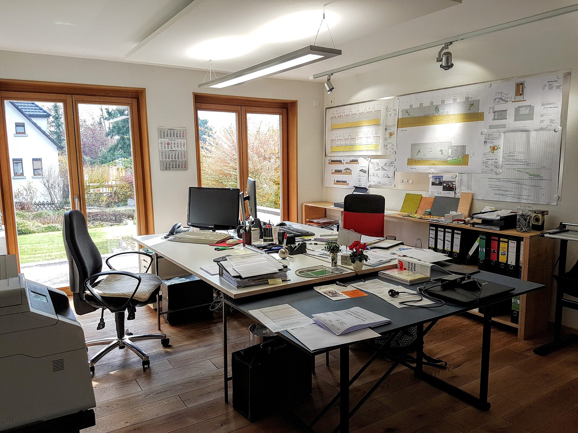 Arbeitsraum im Bürohaus mit großen Fensterelementen und Planwand
