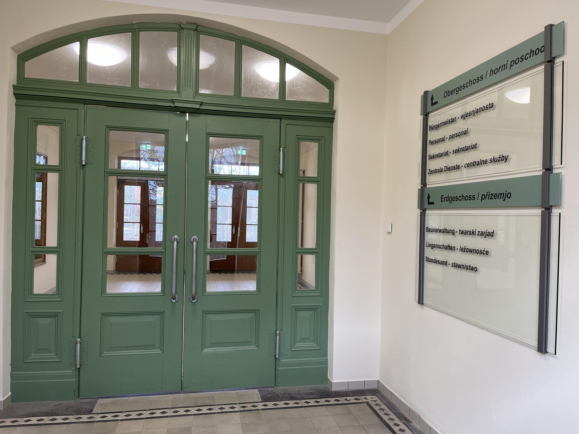 Grüne Tür mit Oberlicht und Wegweisung im Verwaltungszentrum