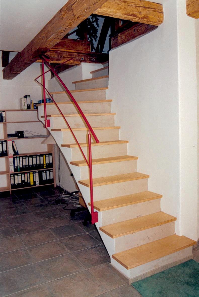 Gerade Holztreppe mit rotem Handlauf unter dem vorhandenen Holztragwerk