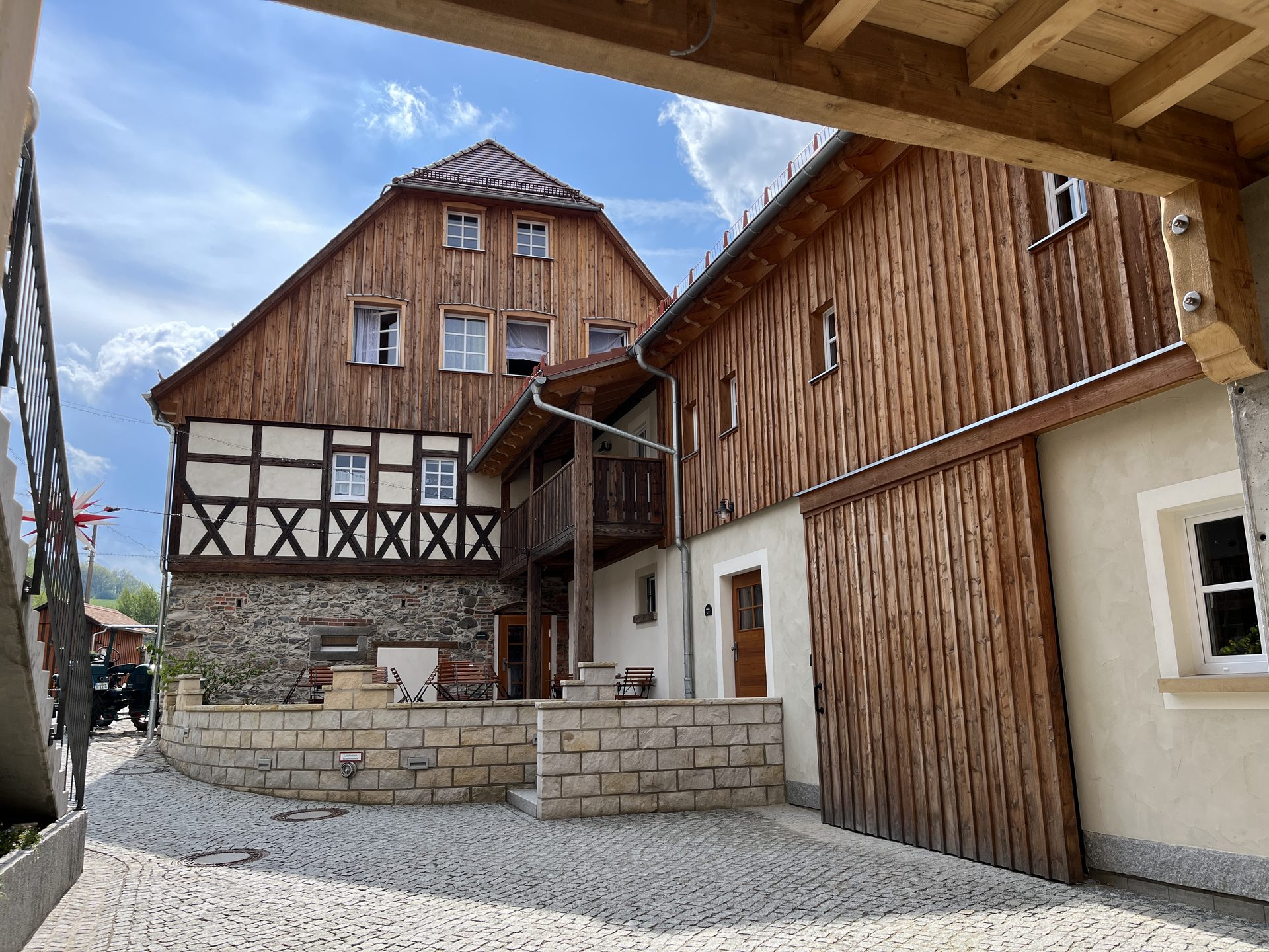 Hofgebäude mit Fachwerk, Holzverschalung und Granit-Stützmauern nach der Sanierung