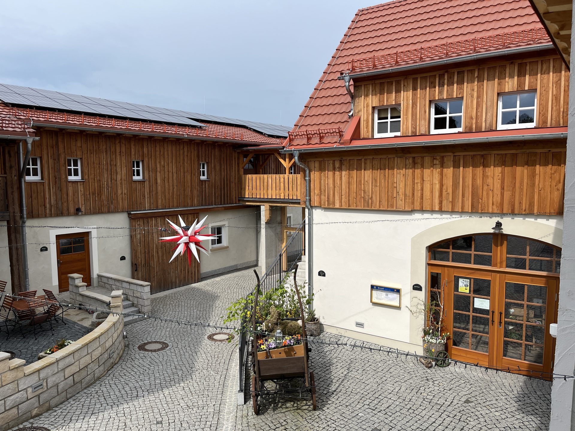 Sanierter Innenhof des Erlebnishofs in Eibau mit Fachwerk, Holzschalung und Granitpflaster