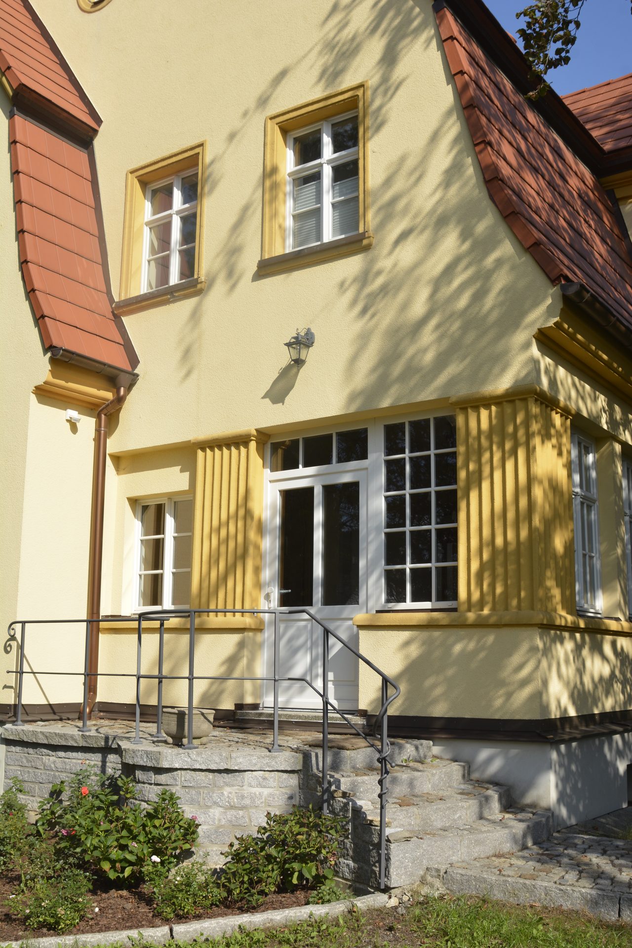 Eingangsseite der sanierten Villa mit Treppe und gegliederter Putzfassade