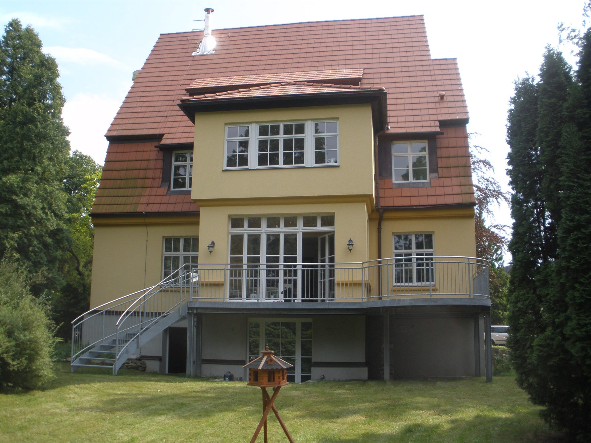 Gartenseite der Villa mit erhöhter Terrasse und seitlicher Außentreppe