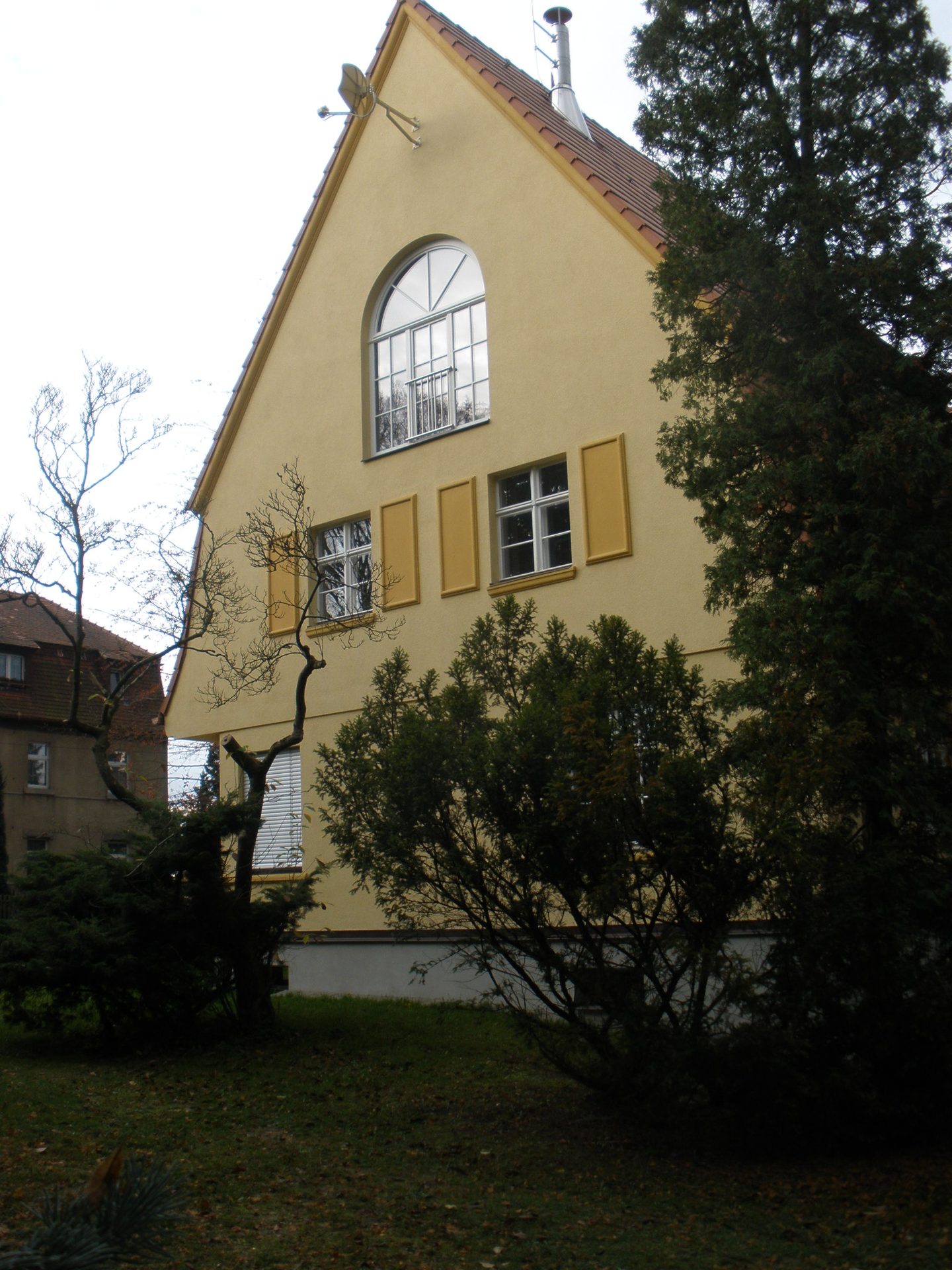 Giebelfassade der Villa mit großem Rundbogenfenster im Dachgeschoss