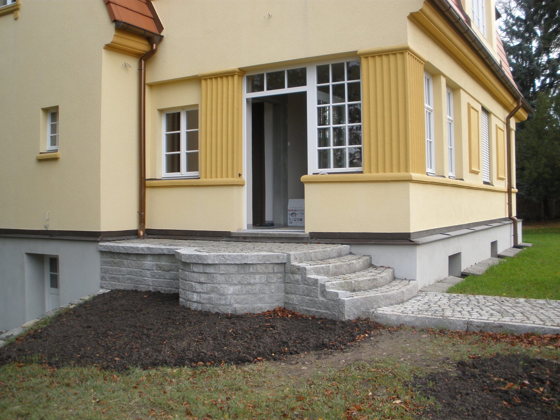 Breite steinerne Stufen vor der verglasten Veranda der Villa