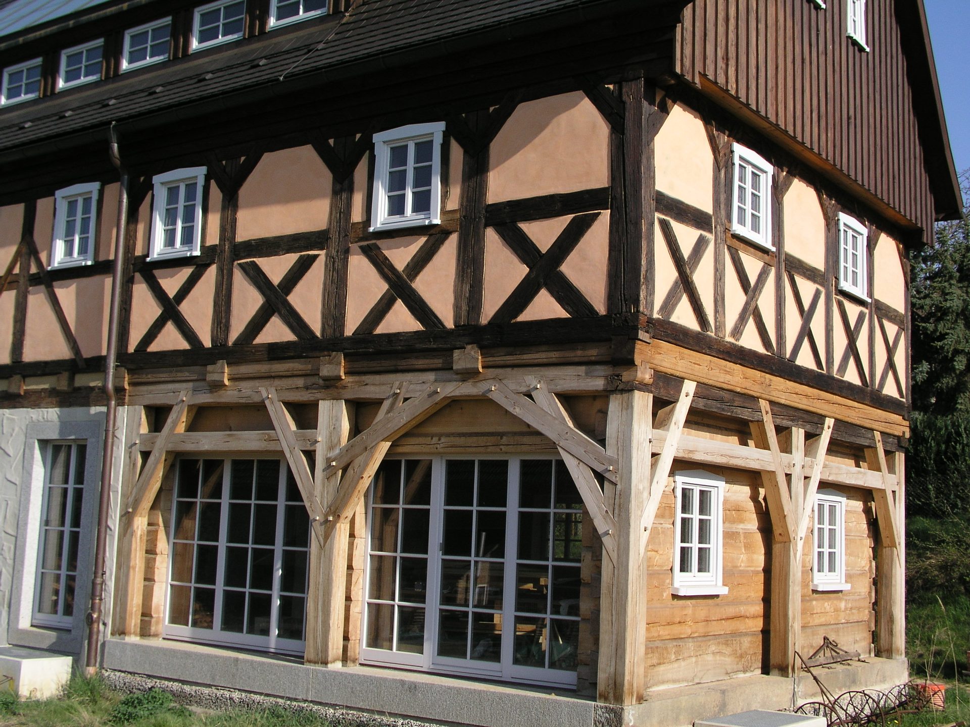 Gebäudeecke mit Umgebindebögen, Fachwerk mit Andreaskreuzen und großen Fenstern im Erdgeschoss