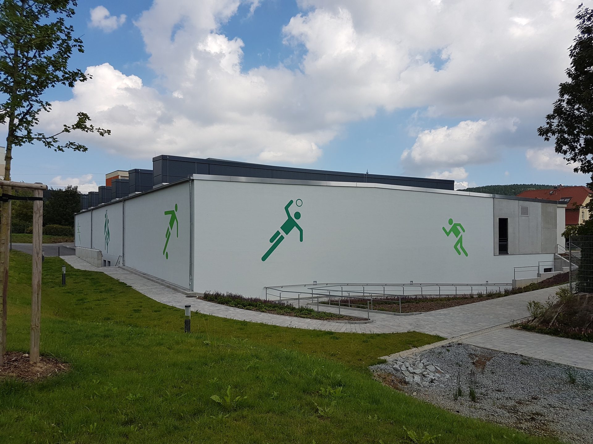 Gebäudeecke der Sporthalle mit Sportler-Piktogrammen auf der Sichtbetonfassade