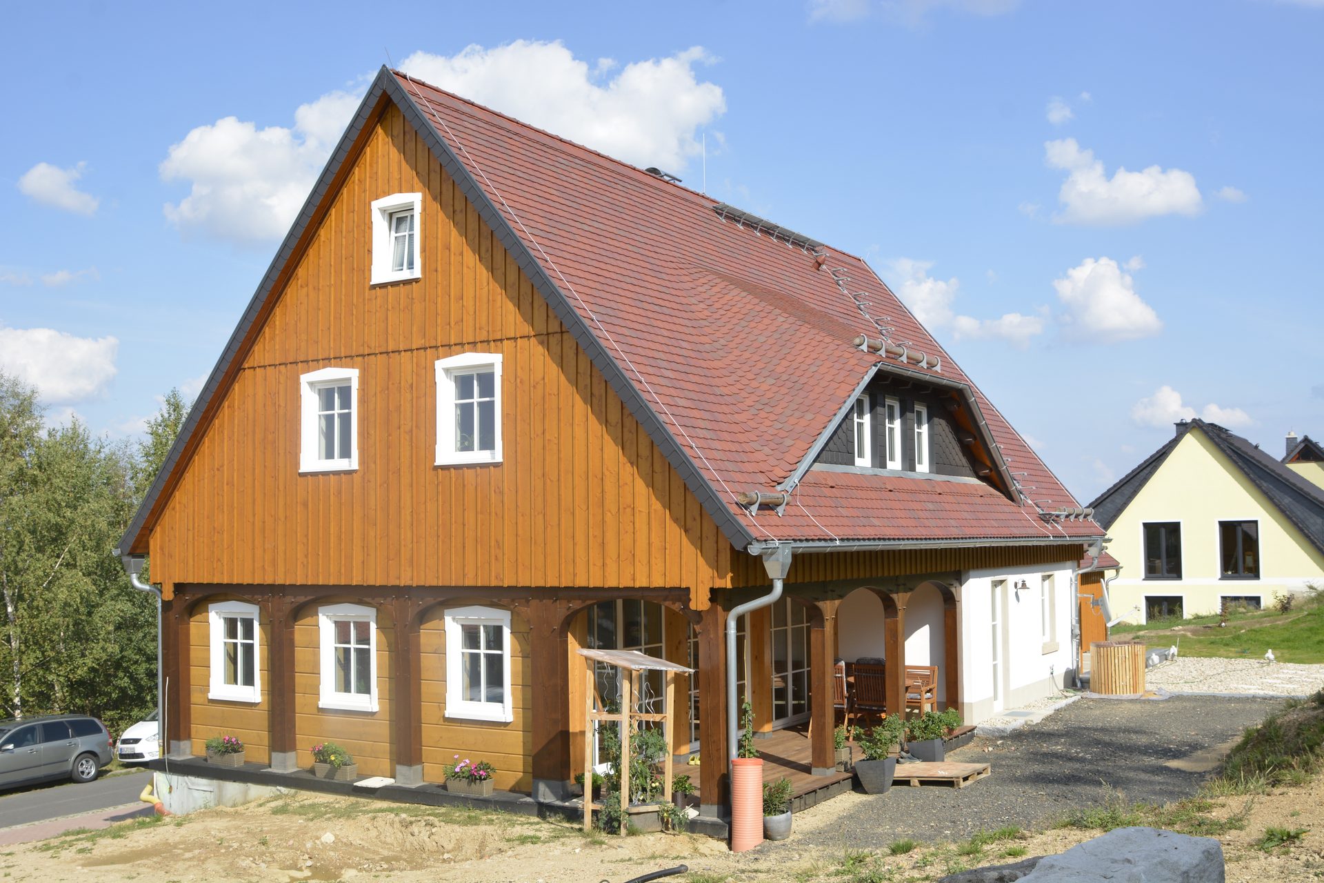 Giebelansicht des Umgebindehauses mit honigfarbener Holzschalung und rotem Ziegeldach
