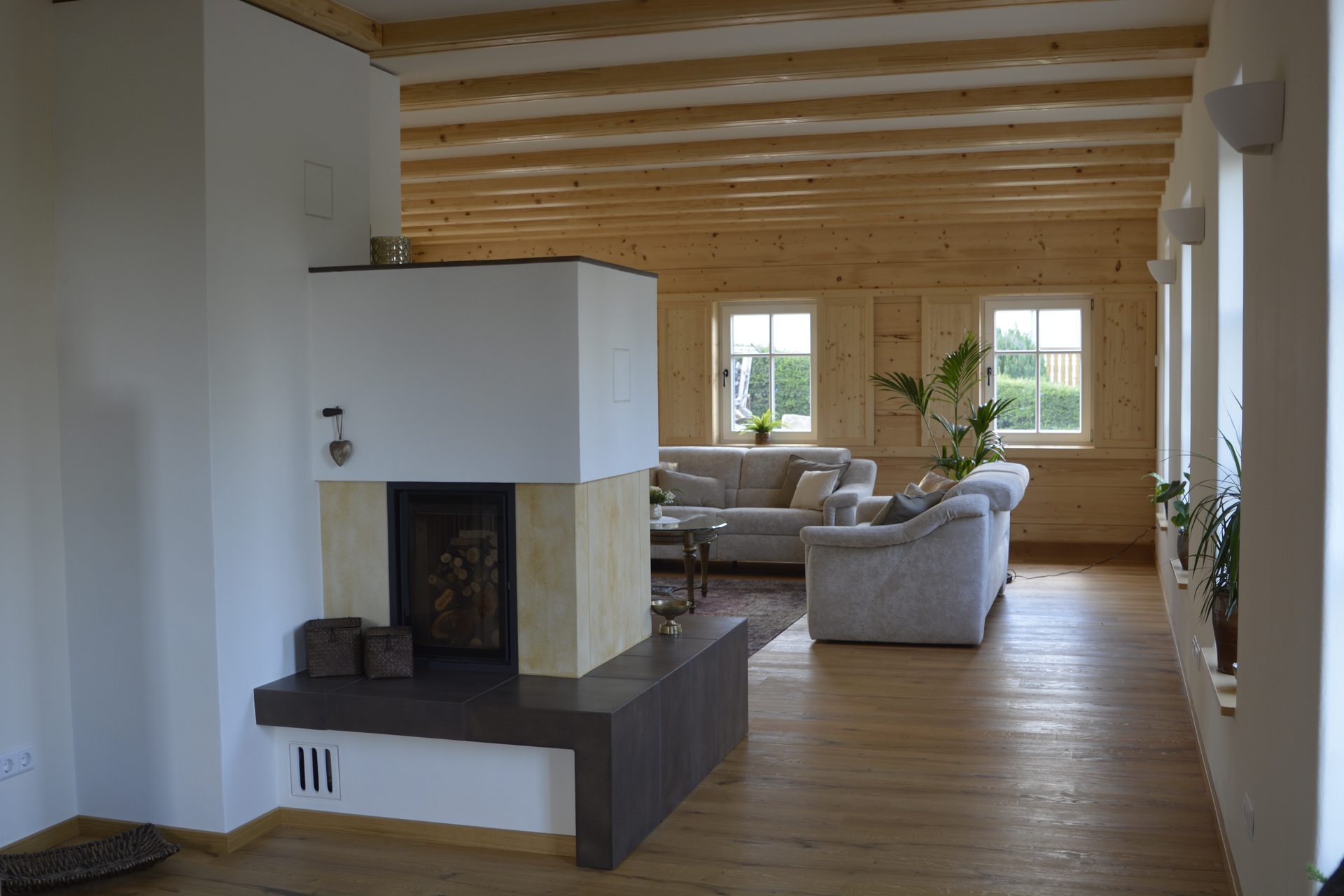 Offener Wohnbereich mit freistehendem Kamin und Holzbalkendecke