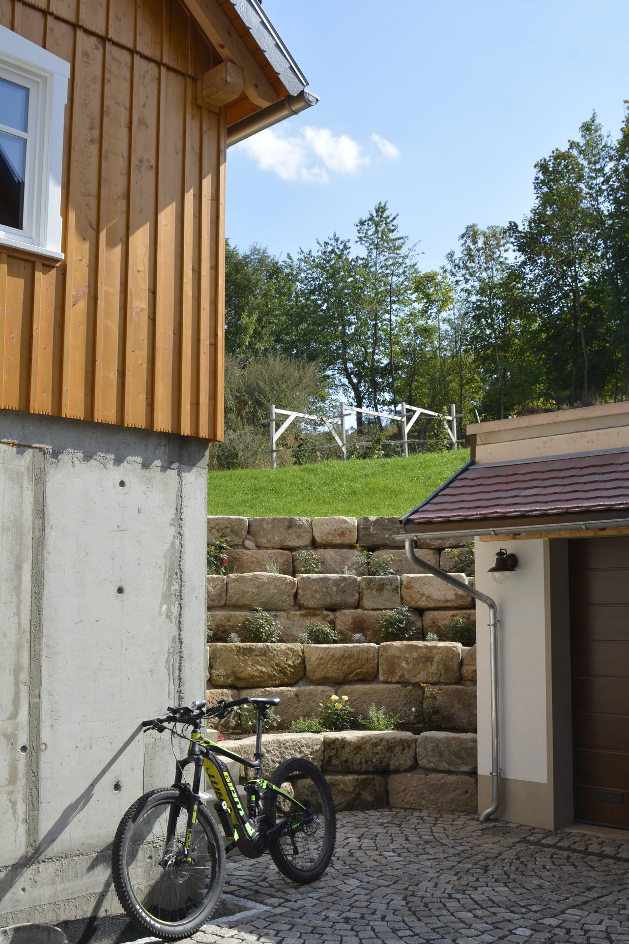 Lärchenschalung, Granit-Stützmauer und Sichtbeton am neu gebauten Umgebindehaus in Waltersdorf
