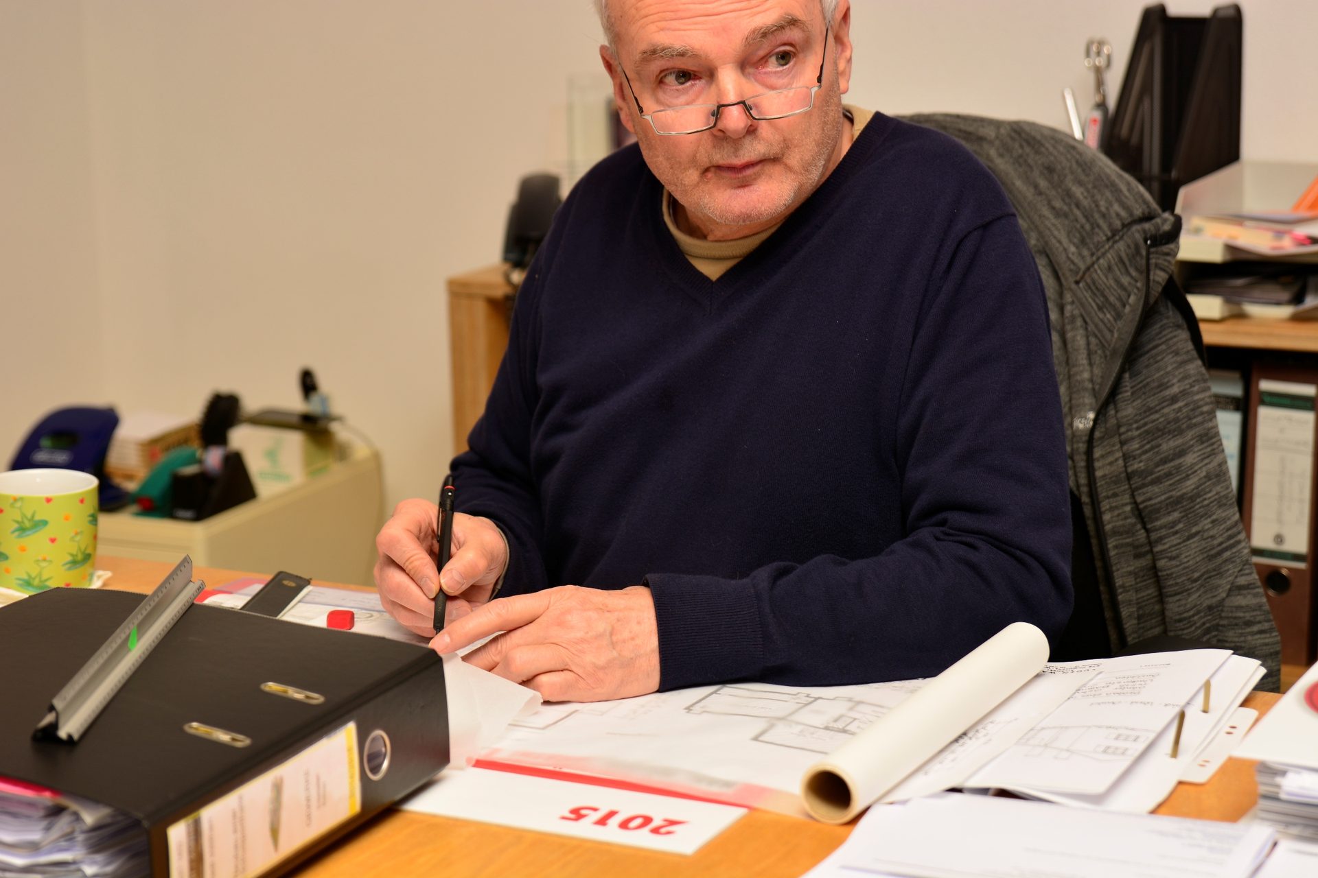 Norbert Dietrich prüft Pläne und Unterlagen am Schreibtisch